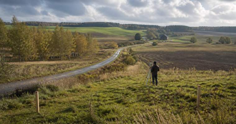 Surveyor assessing a rural Lithuanian plot beside its access road